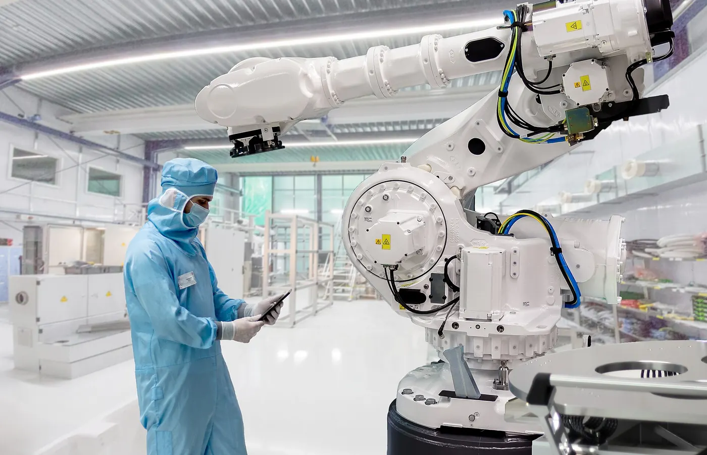 An industrial robot and a technician in a cleanroom production line
